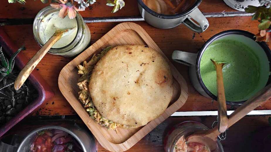 Arepa venezolana rellena servida con salsas tradicionales